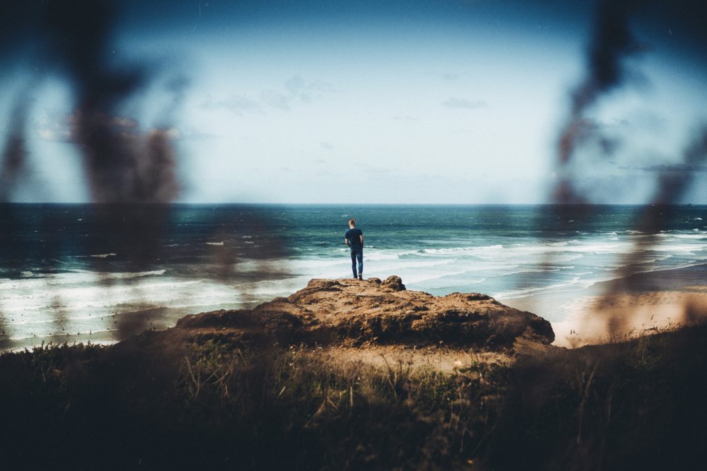 A view of a man standing on a rock at Watergate Bay beach in Cornwall, England